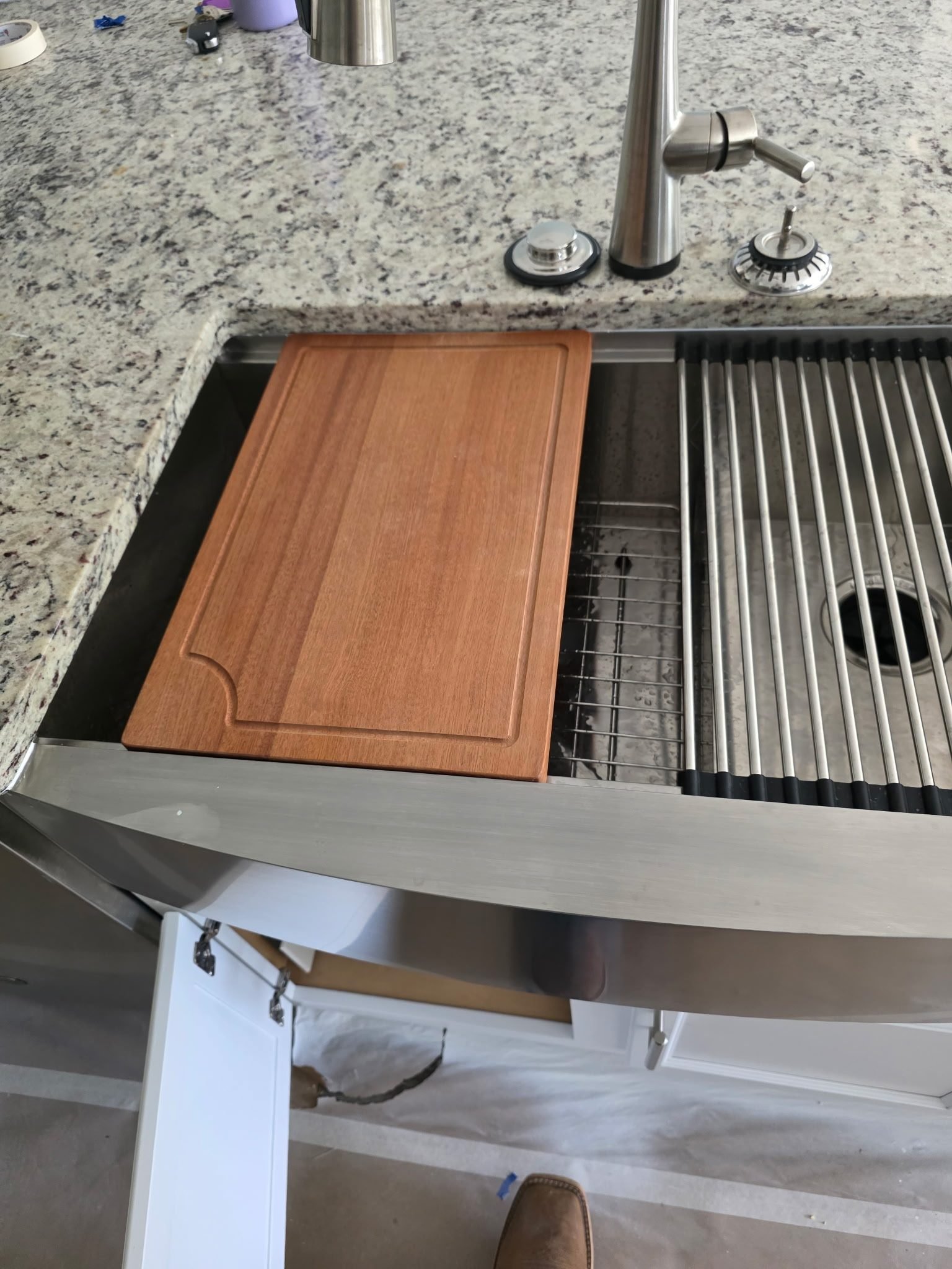 Stainless steel undermount kitchen sink with a brushed nickel faucet and a drying rack inside the basin.