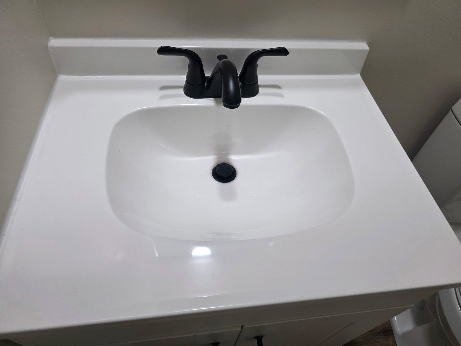 Close-up of a white vanity top sink with a matte black two-handle faucet.
