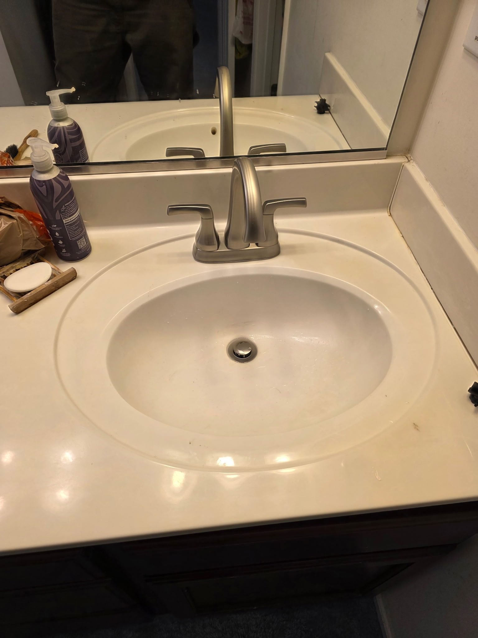 White oval drop-in bathroom sink with a brushed nickel faucet in a finished bathroom.