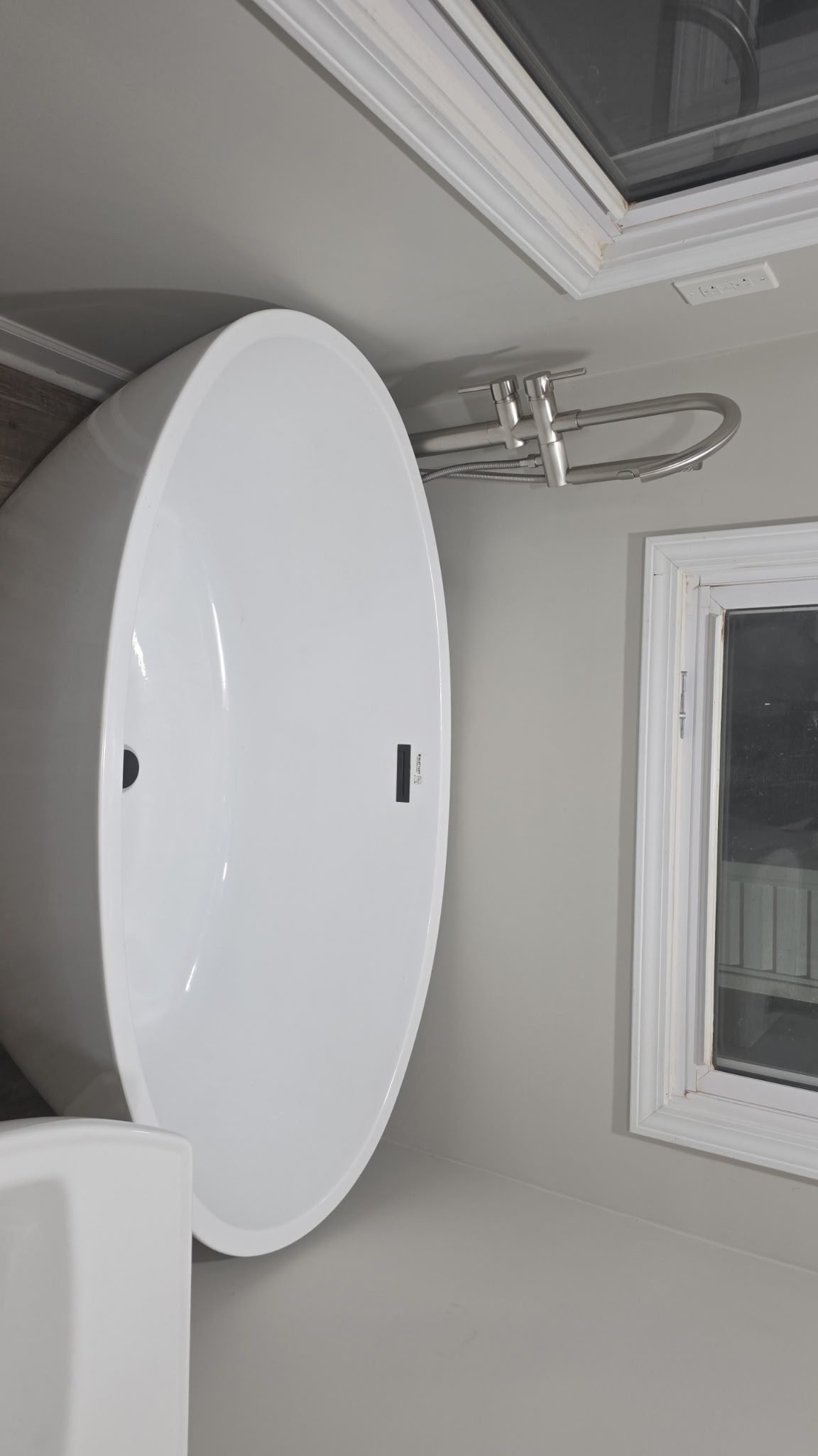 White oval vessel-style bathroom sink mounted on a vanity with a brushed nickel faucet.