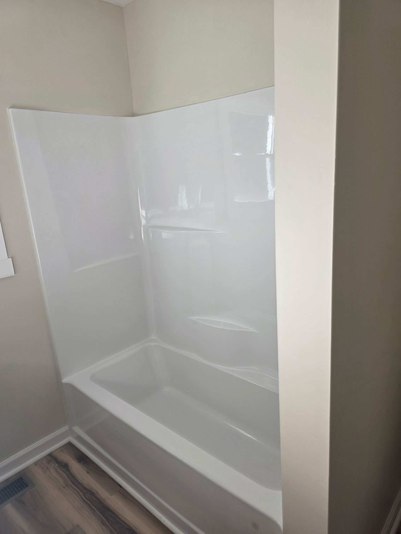 White fiberglass tub-shower surround installed against the wall before fixtures are attached.