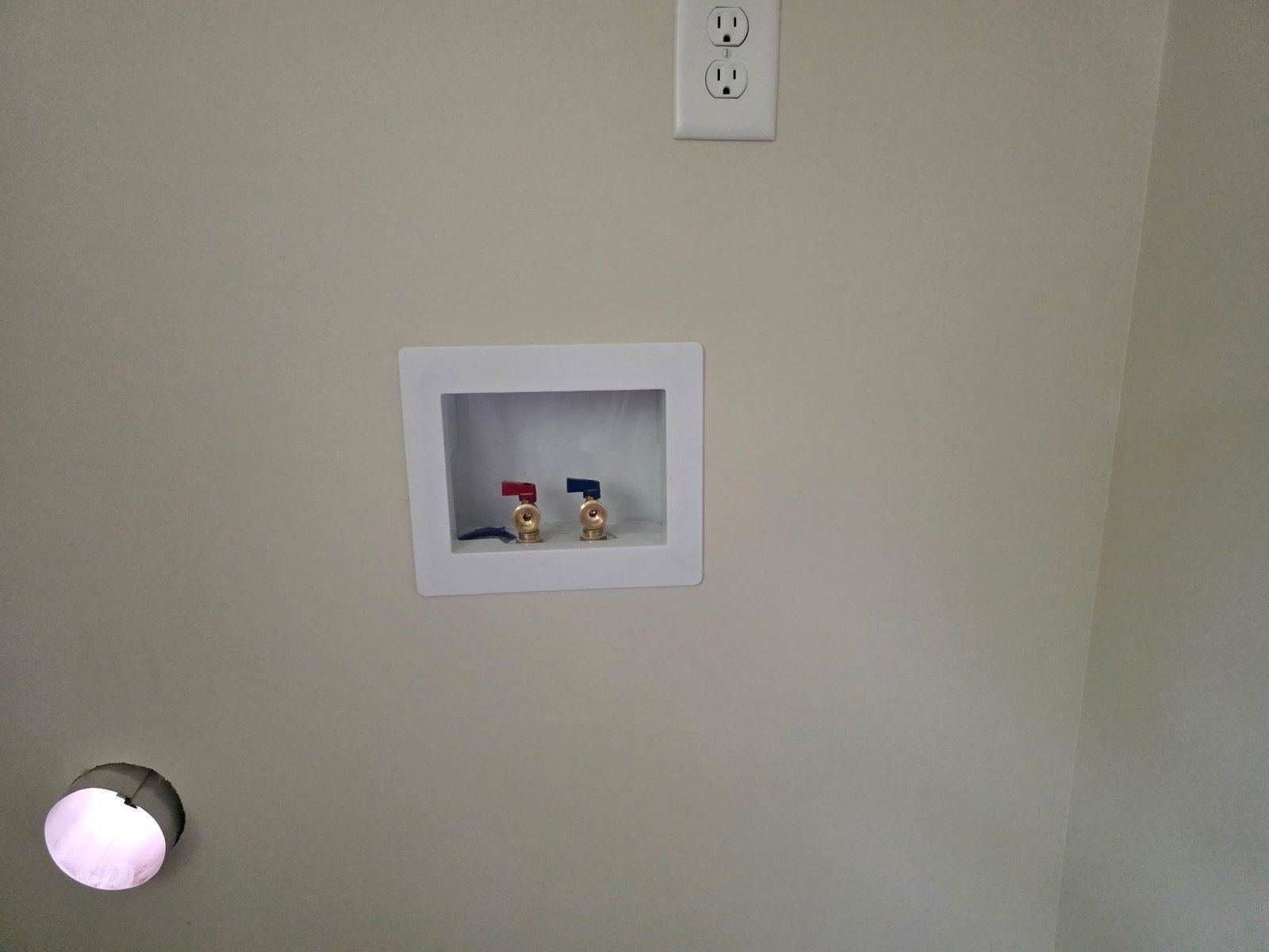 Recessed wall box with red and blue brass washing machine shutoff valves.
