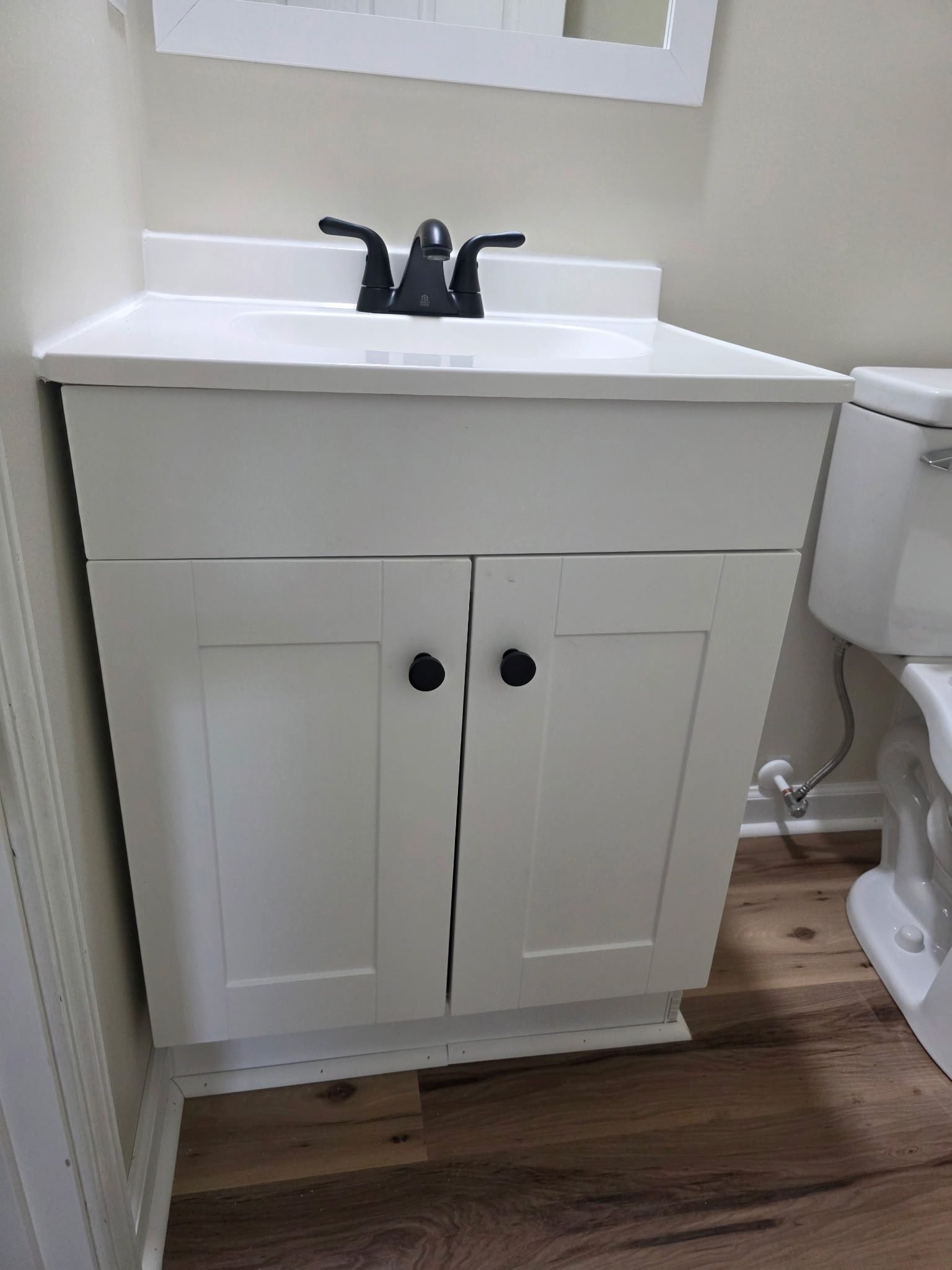 White bathroom vanity sink with a matte black faucet, newly installed beside a toilet.