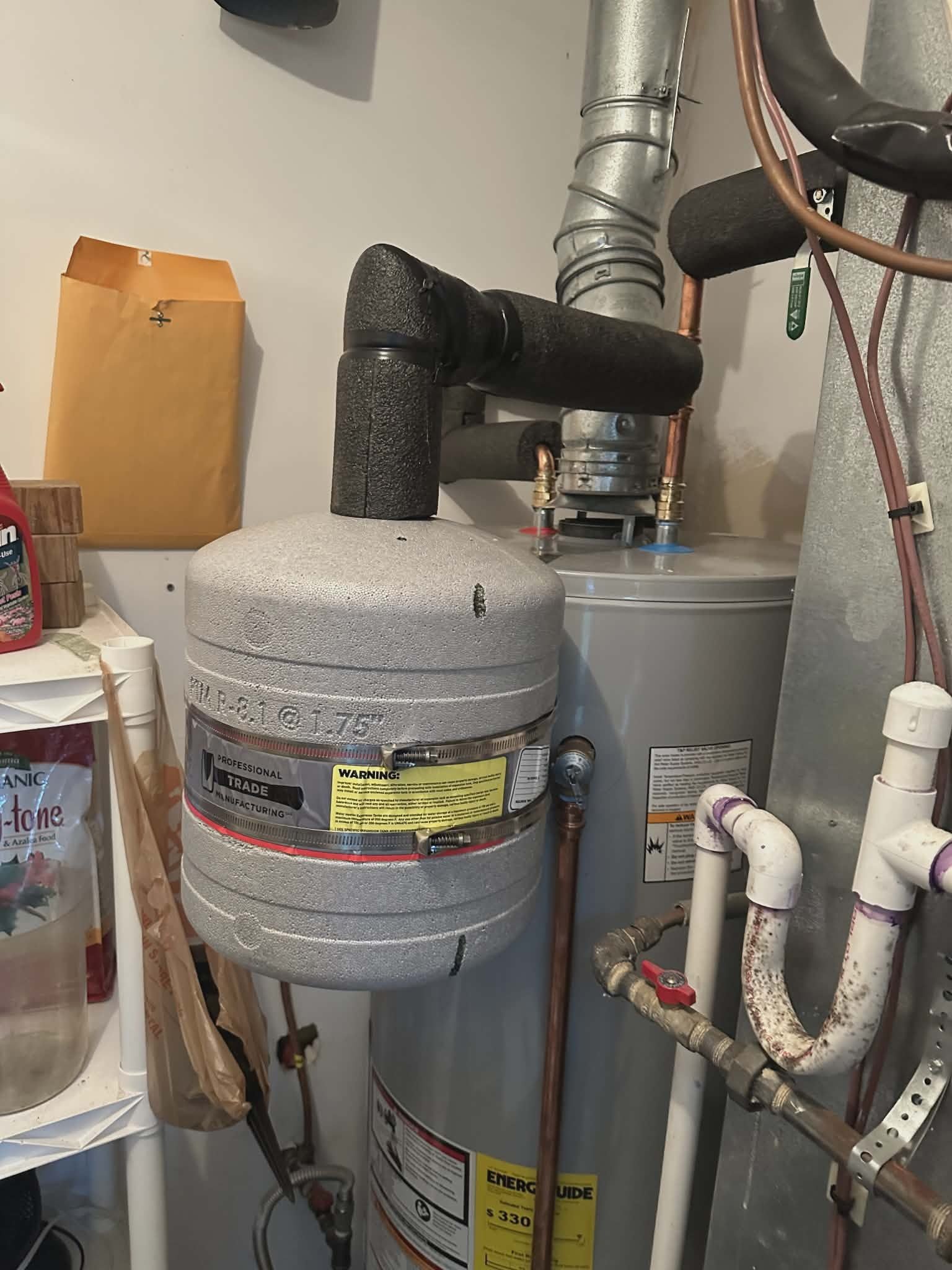 Expansion tank with a venting fitting mounted above a gas water heater.