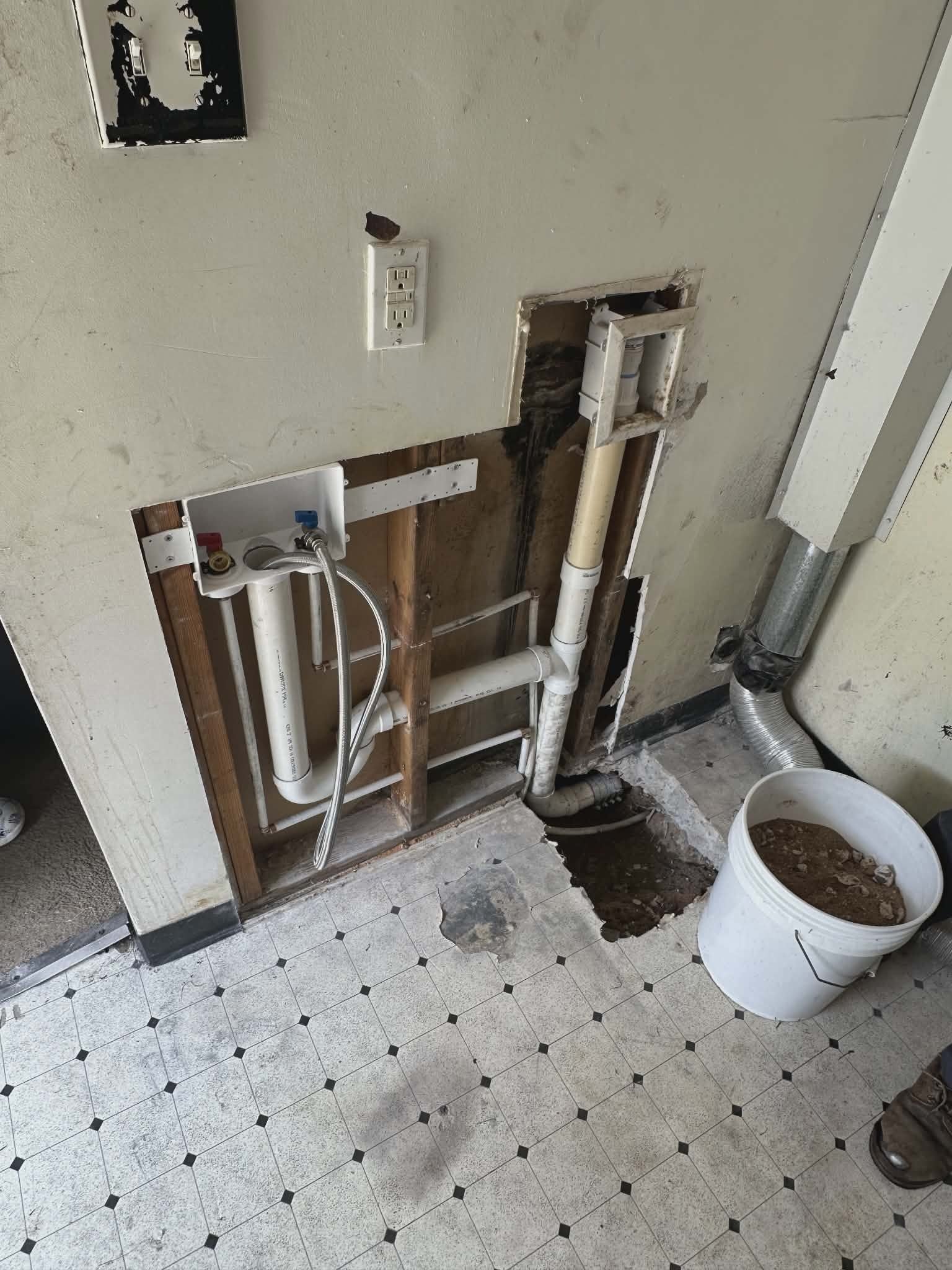Exposed wall cavity with PVC supply shutoff valves and a drain pipe in a kitchen or laundry area.