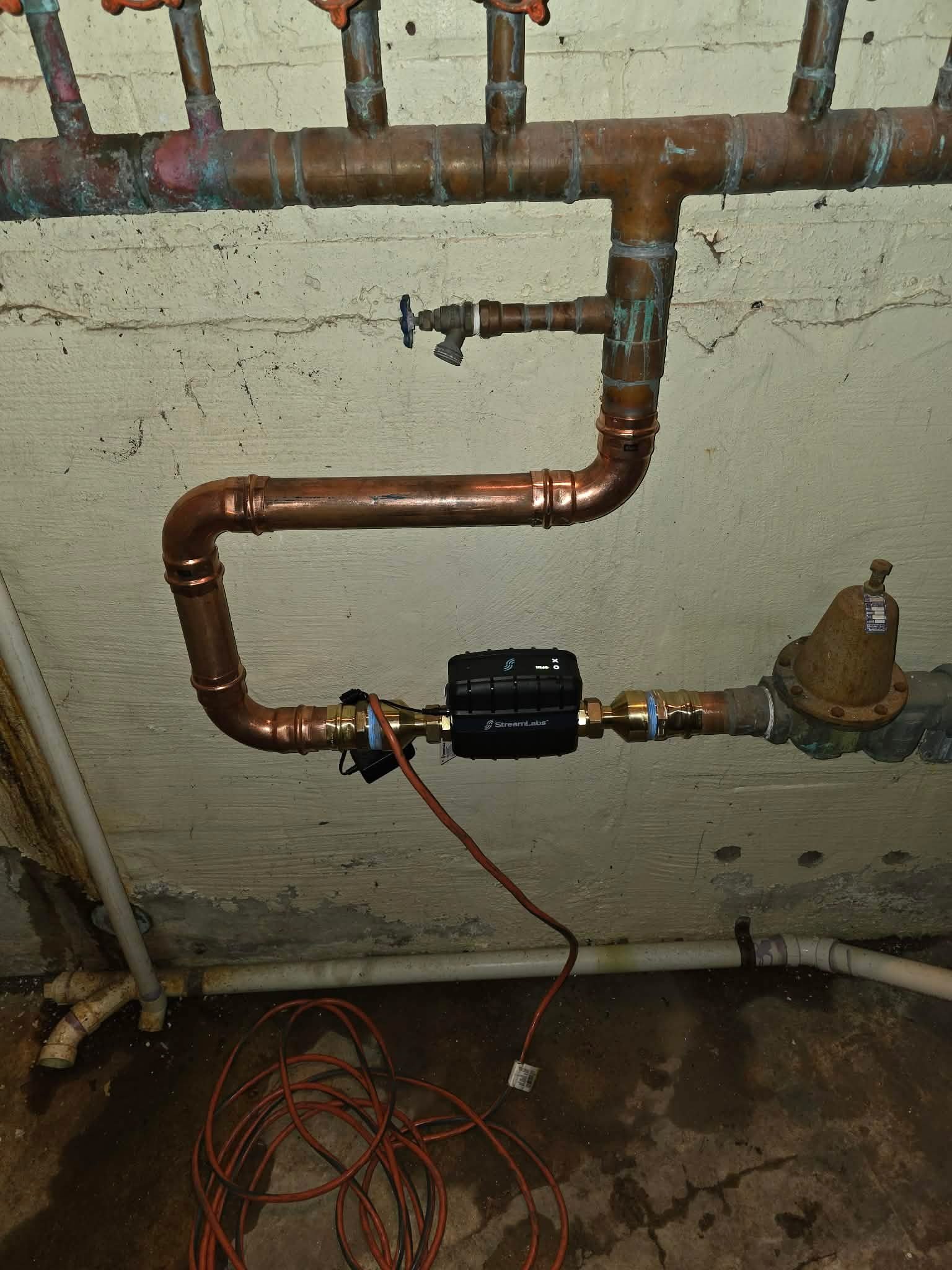 Copper piping with an in-line water treatment device and a brass pressure regulator.
