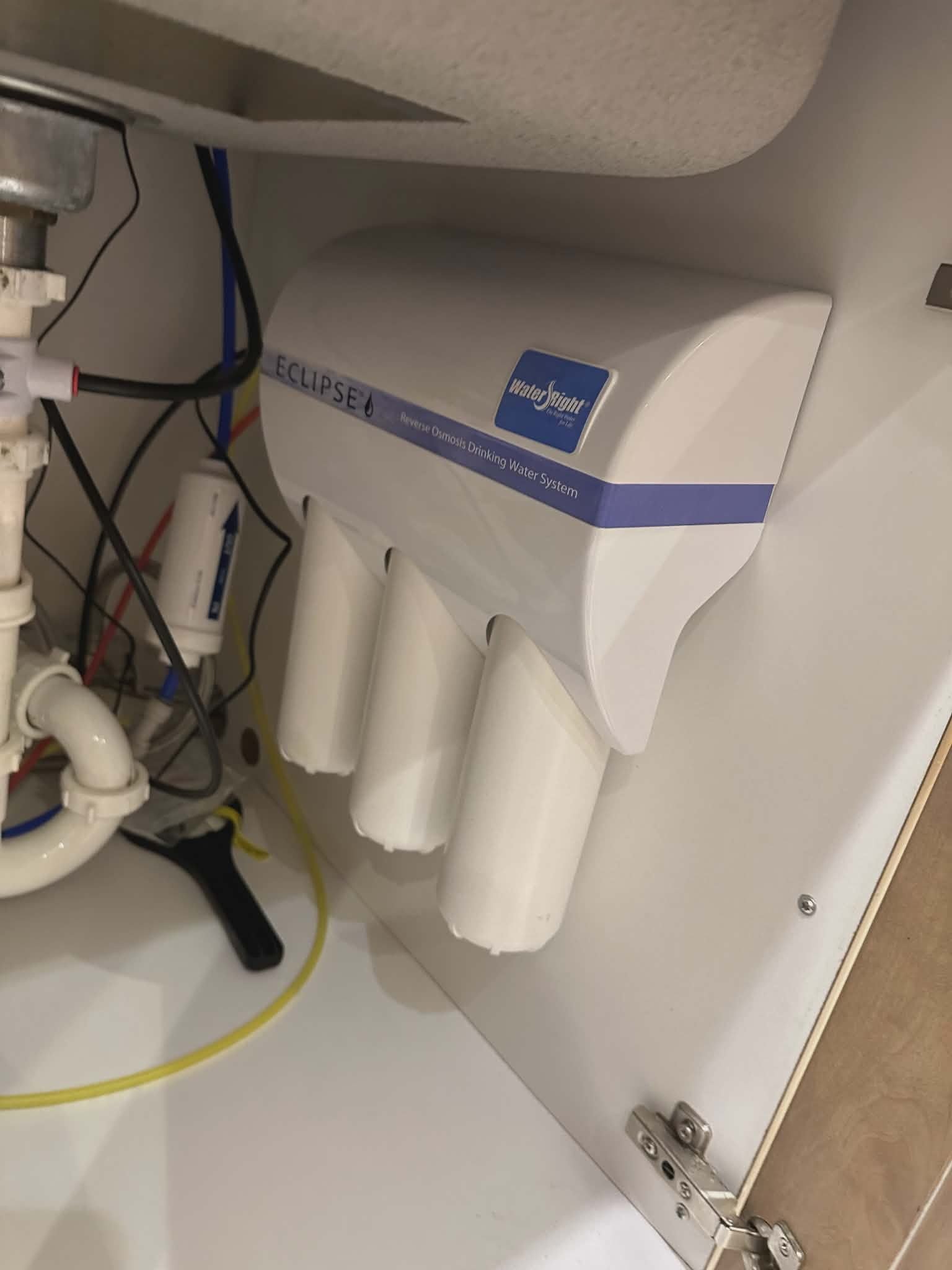 Reverse osmosis drinking water system with three filter canisters mounted under a kitchen sink.