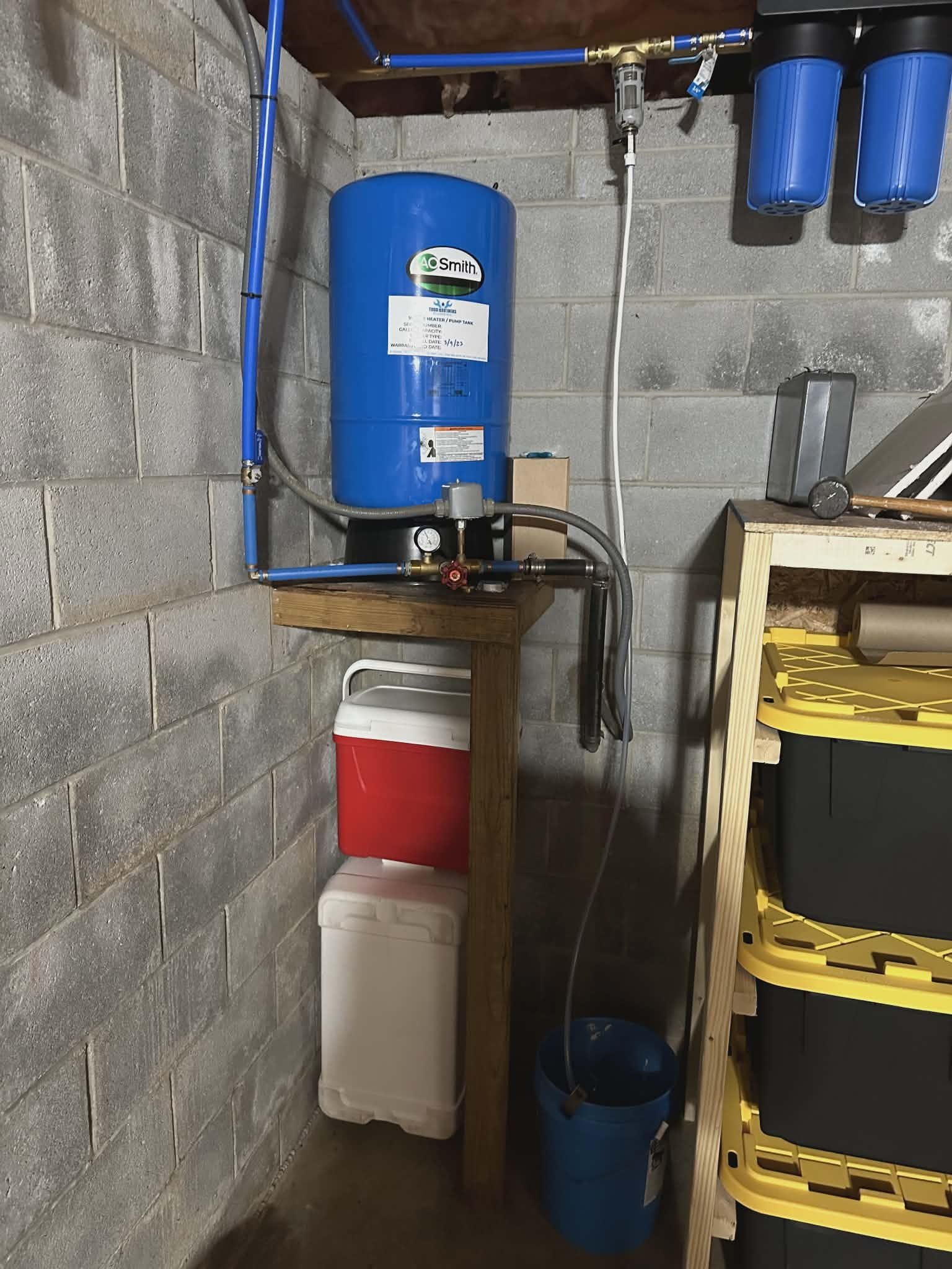 Tankless water heater on a wall with copper supply piping and an electrical panel nearby.