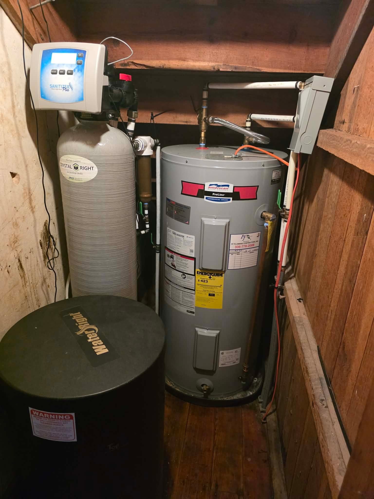 Finished utility closet with a water softener system and gas water heater with supply piping.