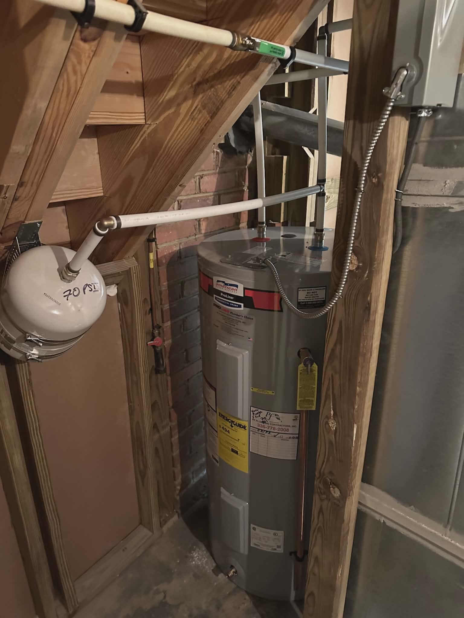 Gas water heater installed in a tight attic nook with a small expansion tank.