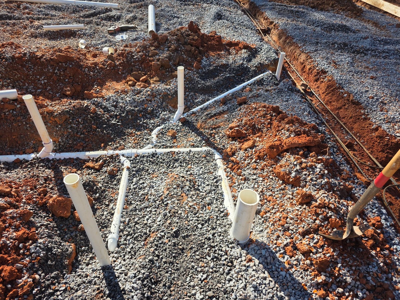 Close-up overhead view of PVC pipe fittings and vertical stub-outs forming a plumbing rough-in network.