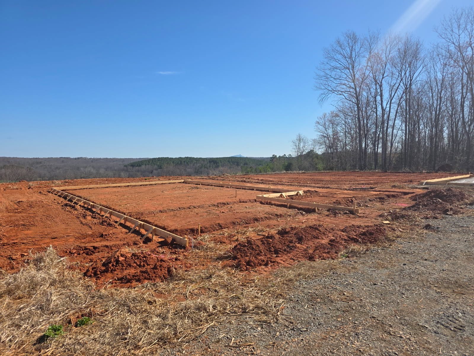 New house foundation footprint staked out with wood forms on a cleared lot.