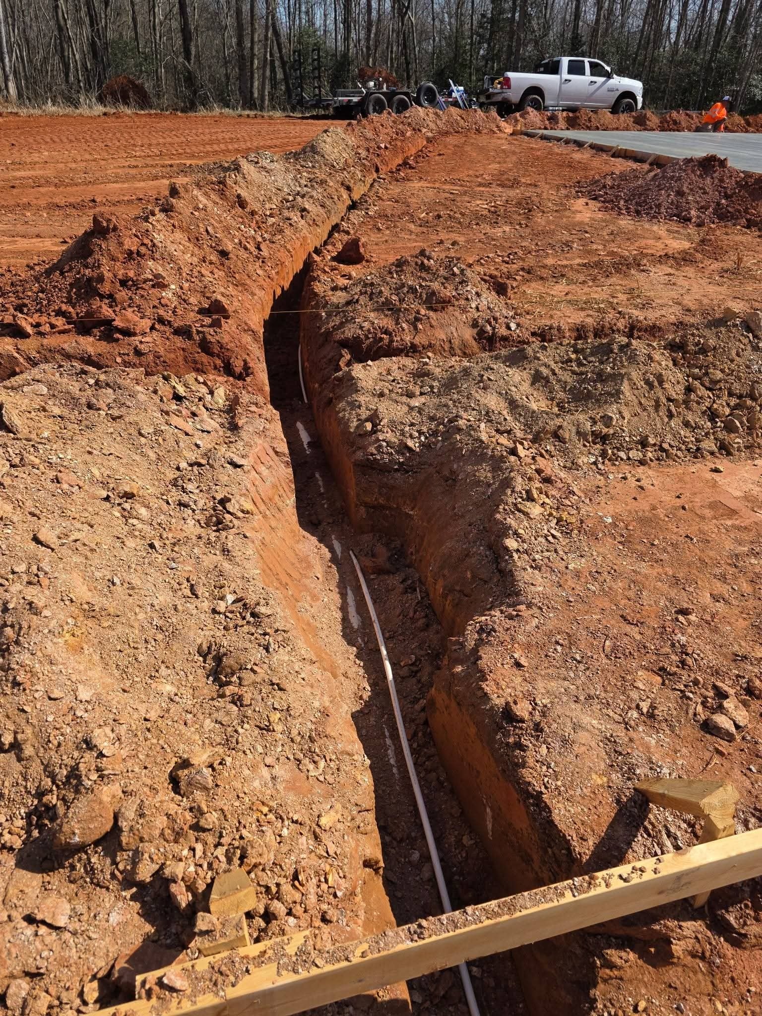 Long trench with pipe running along the bottom and a parallel trench beside it.